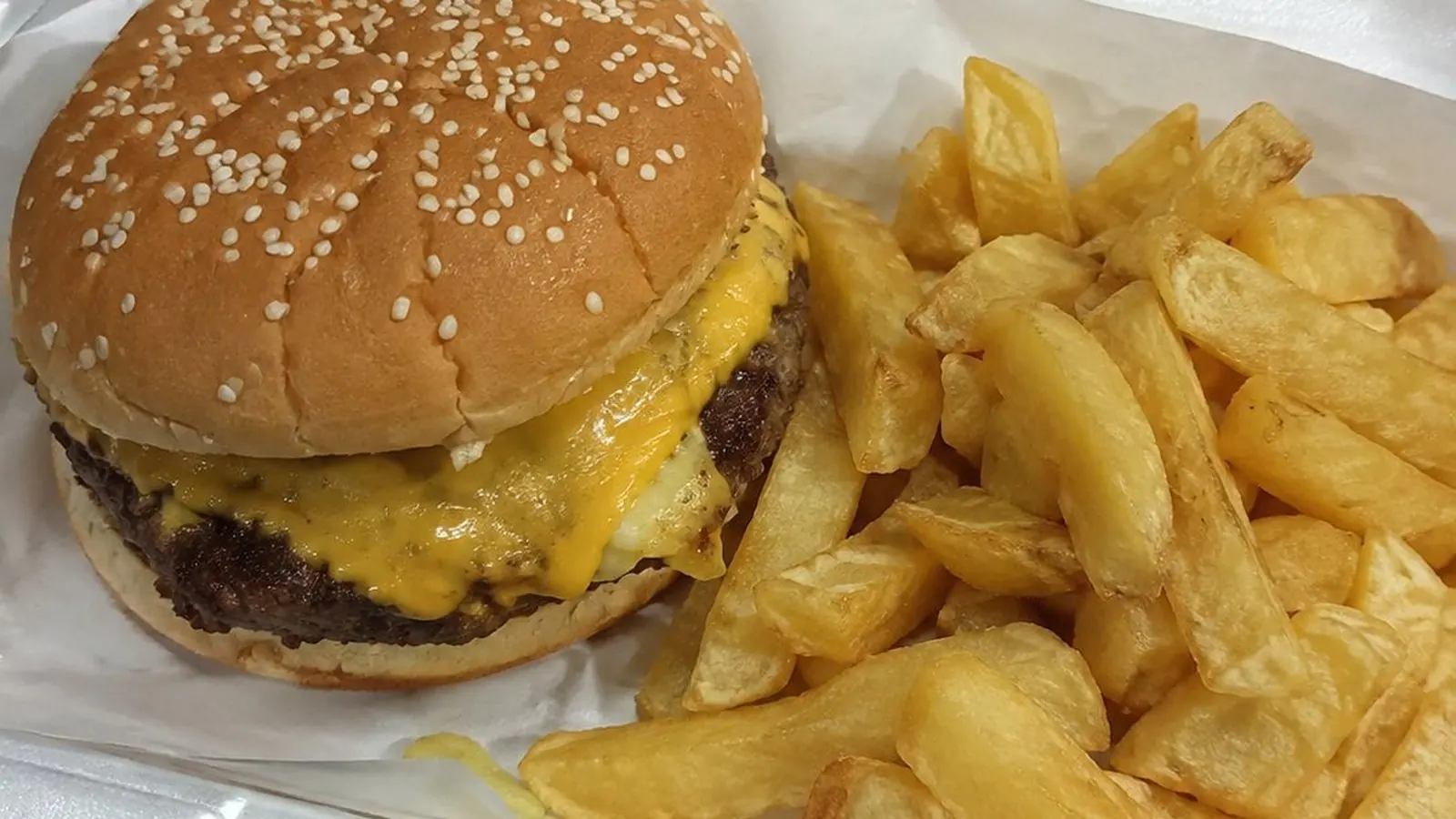 Cheeseburger and chips in a takeaway tray