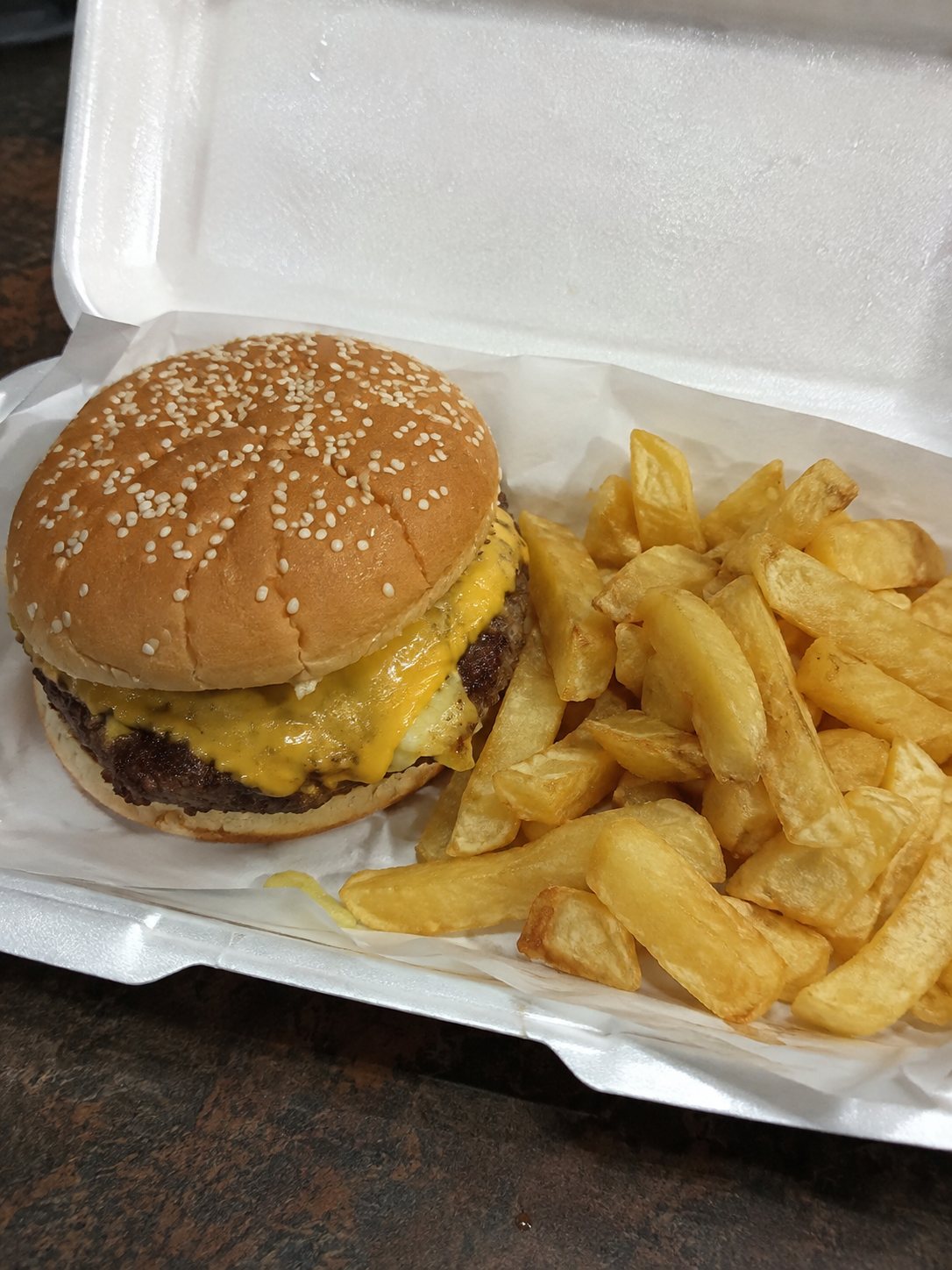 Cheeseburger and chips in a takeaway tray