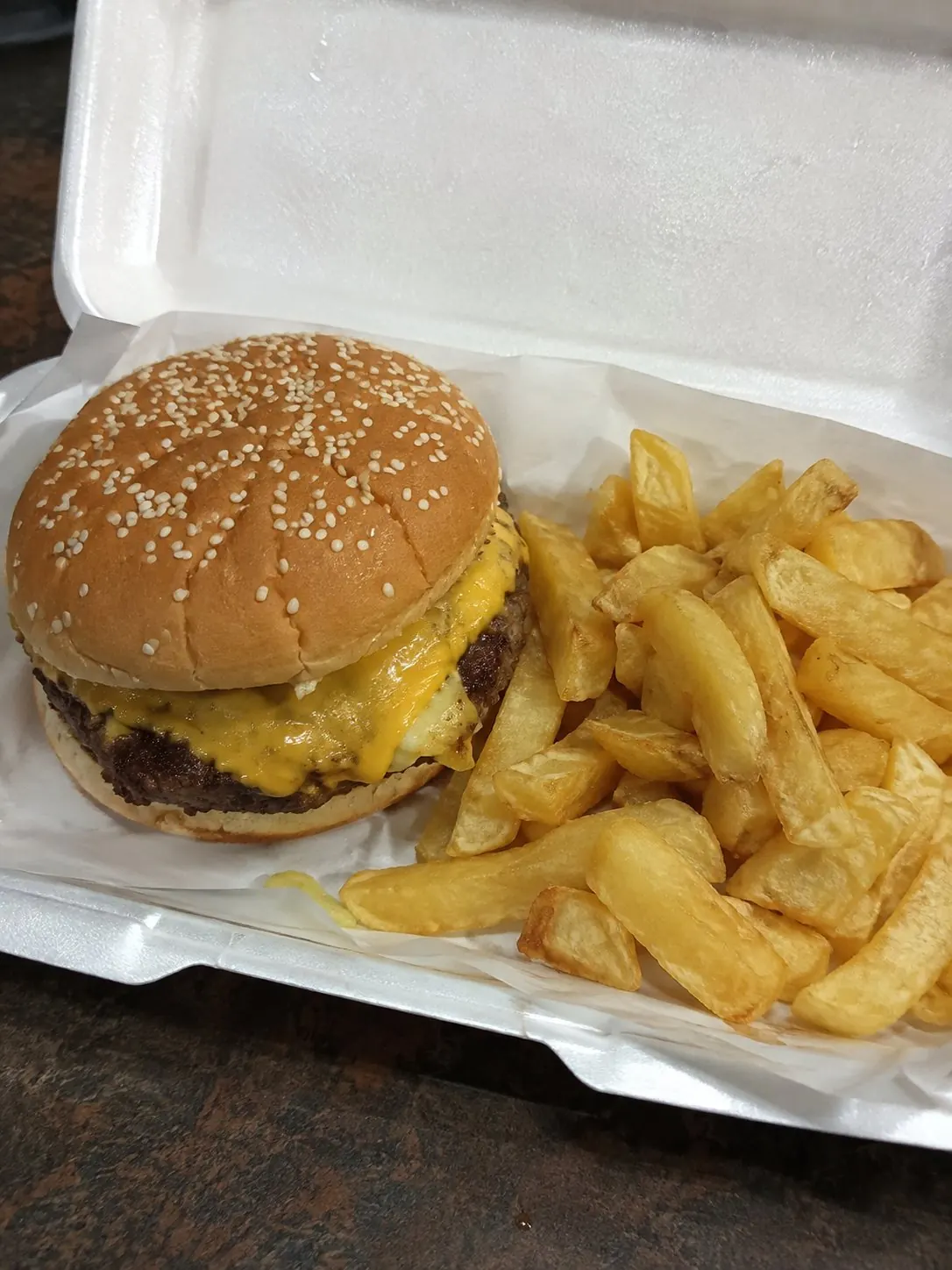Cheeseburger and chips in a takeaway tray